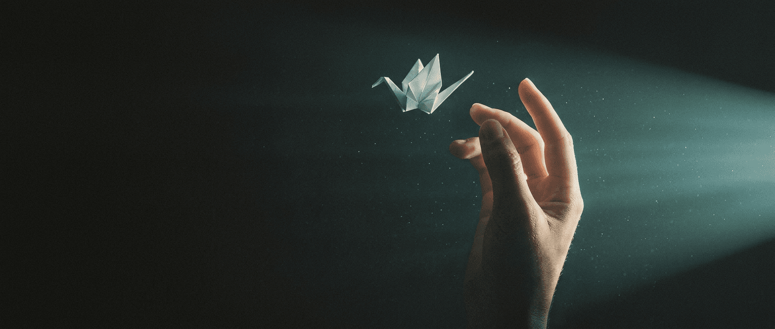 Una mano abierta hacia la luz, con una grulla de papel.